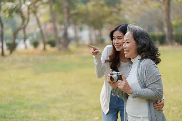 아시아의 어머니와 추억을 포착하기 카메라를 가지고 공원을 — 스톡 사진