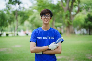 Çok ırklı gönüllüler, kamu parkındaki kirliliği azaltmak için geri dönüşüm için plastik atık toplamak amacıyla ellerinde siyah çöp torbaları tutarak zamanlarını bağışlıyorlar.