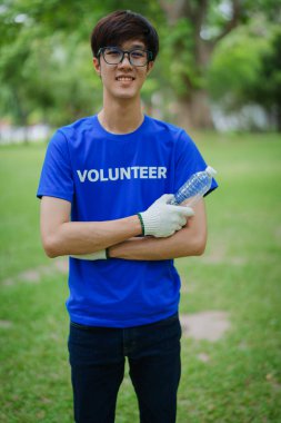 Çok ırklı gönüllüler, kamu parkındaki kirliliği azaltmak için geri dönüşüm için plastik atık toplamak amacıyla ellerinde siyah çöp torbaları tutarak zamanlarını bağışlıyorlar.