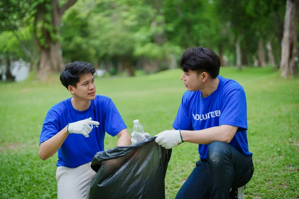 stock image Multiethnic volunteers donate their time holding black garbage bags to collect plastic waste for recycling to reduce pollution in a public park