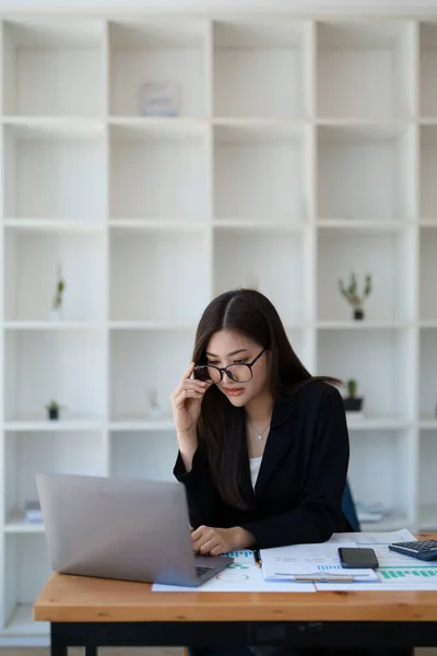 一位深思熟虑的亚洲女商人的画像 她一边看财务报表 一边用桌上的电脑制定营销计划 — 图库照片