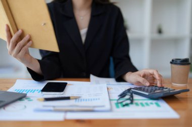 Genç Asyalı kadınlar, vergi makbuzlarını internetten ödemeden önce ev sayımında mali evraklarla çalışıyorlar. Ekonomi tasarrufu, denetim kavramları ve tasarruf şansı bulmaktan memnun olacak bir bütçe planlıyorlar..