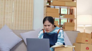 Çevrimiçi pazarlama paketi ürünleri ve KOBİ teslimat konseptiyle bilgisayar laptopu kullanarak gülümseyen bağımsız Asyalı bir kadının küçük işletme girişimciliğini başlatıyorum. Yüksek kalite 4k