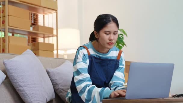 创业的独立亚洲女性小企业主使用电脑笔记本电脑笑容满面 在网上营销包装项目和中小企业交付理念上取得了可喜的成功 高质量4K — 图库视频影像