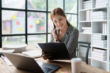 Danışman, danışman, Asyalı iş kadını bilgisayarda çalışıyor ve akıllı telefon konuşmaları yapıyor. Finansal ve pazarlama işi planlama şirketi kârları, pazarlama bütçesi.