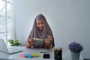 Finansal, Planlama, Pazarlama ve Muhasebe, iş yerindeki belge ve hesap makineleriyle mali durumları kontrol eden Müslüman kadın çalışanın portresi.