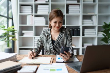 Danışman, danışman, Asyalı iş kadını bilgisayarda çalışıyor ve akıllı telefon konuşmaları yapıyor. Finansal ve pazarlama işi planlama şirketi kârları, pazarlama bütçesi.