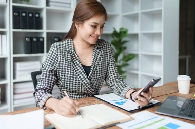 Danışman, danışman, Asyalı iş kadını bilgisayarda çalışıyor ve akıllı telefon konuşmaları yapıyor. Finansal ve pazarlama işi planlama şirketi kârları, pazarlama bütçesi.