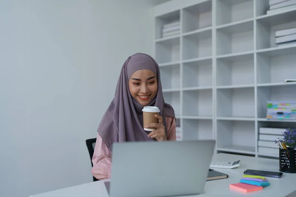 노트북 컴퓨터와 커피를 마시는 이슬람 여성의 — 스톡 사진