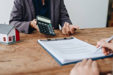 Teminat, mortgage, sözleşme, sözleşme, kontrat, emlakçı ya da banka memuru elinde hesap makinesi olan bir müşteri ile anlaşma imzalamadan önce bir ev satın almak için teklif sunar..