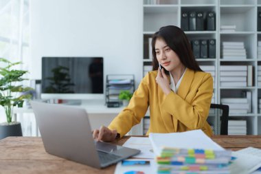 Danışman, danışman, Asyalı iş kadını bilgisayarda çalışıyor ve akıllı telefon konuşmaları yapıyor. Finansal ve pazarlama işi planlama şirketi kârları, pazarlama bütçesi.