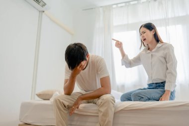 Aile içi şiddet, Asyalı eş, tehdit eden koca, yatakta yan yana otururken onu kucaklayan korkmuş aile lideri.