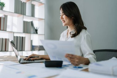 Genç Asyalı kadınlar, vergi makbuzlarını internetten ödemeden önce ev sayımında mali evraklarla çalışıyorlar. Ekonomi tasarrufu, denetim kavramları ve tasarruf şansı bulmaktan memnun olacak bir bütçe planlıyorlar..