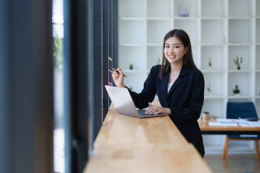 Genç Asyalı güzel iş kadını not defterini kullanarak mali belge, vergi, döviz, muhasebe ve mali danışman üzerinde çalışmayı planlıyor..