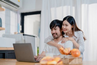 Genç ve mutlu aile çiftimiz dizüstü bilgisayar ekranlarına bakıyor, ekipleri okuyor. Eş, kocasını çok mutlu bir şekilde kucaklıyor. Hafta sonları mutfakta oturuyor.