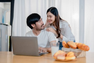 Genç ve mutlu aile çiftimiz dizüstü bilgisayar ekranlarına bakıyor, ekipleri okuyor. Eş, kocasını çok mutlu bir şekilde kucaklıyor. Hafta sonları mutfakta oturuyor.