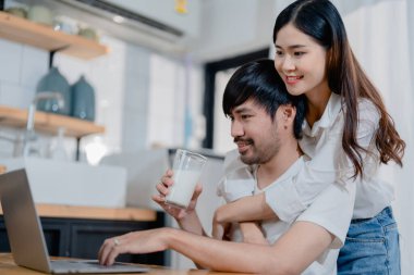 Genç ve mutlu aile çiftimiz dizüstü bilgisayar ekranlarına bakıyor, ekipleri okuyor. Eş, kocasını çok mutlu bir şekilde kucaklıyor. Hafta sonları mutfakta oturuyor.