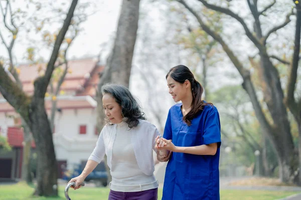 Fisioterapeuta Mujer Sostiene Una Paciente Anciana Caminando Parque Para Fortalecer —  Fotos de Stock