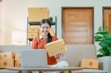 Bağımsız Asyalı kadın çevrimiçi satıcının müşterilere ve KOBİ dağıtım konseptine göndermek üzere ürünlerini paketleyen küçük işletme girişimcisi başlatılıyor.