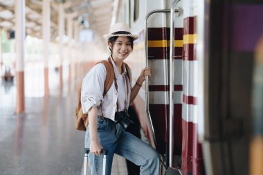 Turistler tren istasyonunda yolculuklarını beklerken mutlu yüz ifadeleri sergiliyorlar.