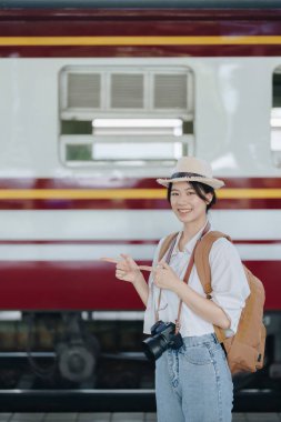 Turistler tren istasyonunda yolculuklarını beklerken mutlu yüz ifadeleri sergiliyorlar.