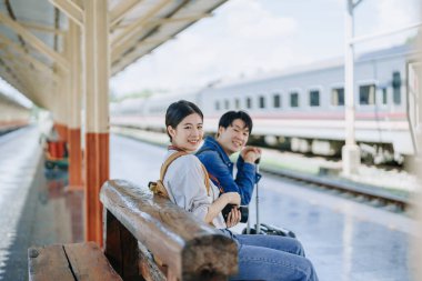 Tren istasyonunda beklerken hatıraları kaydetmek için kamerayla seyahat eden genç bir çift. Seyahat kavramları.