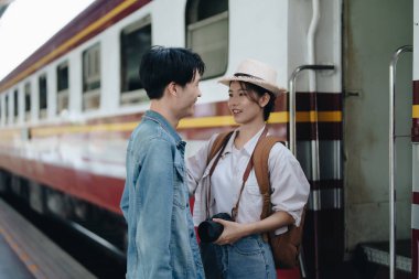 Tren istasyonunda yolculuklarını beklerken sevgi ve mutluluklarını tatlı bir şekilde gösteren turist çiftler.