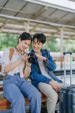 Tren istasyonunda beklerken hatıraları kaydetmek için kamerayla seyahat eden genç bir çift. Seyahat kavramları.