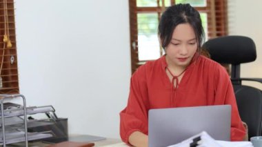 İş sahibi ya da Asyalı kadın pazarlamacılar evde hesap makinesi, defter ve bilgisayar kullanıyorlar. Yüksek kalite 4k görüntü
