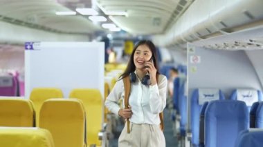 Asyalı tatlı bir genç kız, yıllık seyahat konsepti için uçakta arkadaşıyla telefonda konuşuyor. Yüksek kalite 4k görüntü