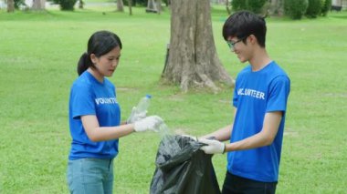Çok ırklı gönüllüler zamanlarını, kamu parkındaki kirliliği azaltmak için geri dönüşüm için plastik atık toplamak amacıyla ellerinde siyah çöp torbalarıyla harcıyorlar. Yüksek kalite 4k görüntü