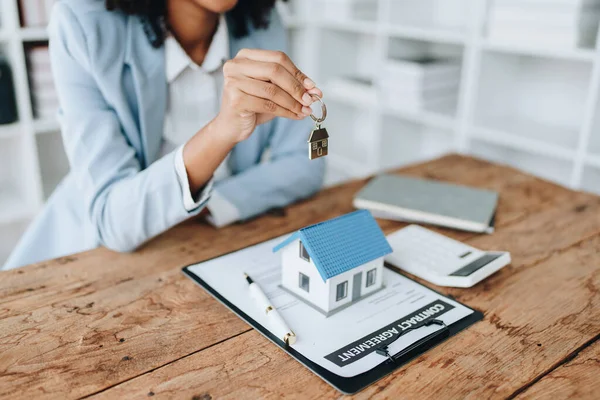 Garanti, ipotek, anlaşma, sözleşme, imza, kadın Afro-Amerikan müvekkil, emlakçı ya da banka memuruyla arazi kredisi imzalamak için elinde kalem tutan, sigorta kavramları.