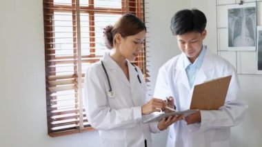 Genç Asyalı kadın doktor, işe gitmek için tablet kullanan bir hastayı ameliyata hazırlamak için danışmanla konuşuyor. Yüksek kalite 4k görüntü