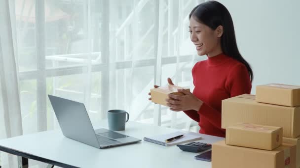 中小企業 いくつか お客様とコンピュータビデオ会議を使用してアジアの美しい女性は 製品ボックスのサイズを確認し 顧客に配信される価格を伝えるために — ストック動画
