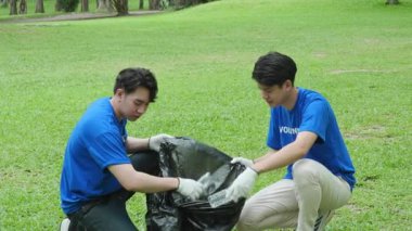 Çok ırklı gönüllüler zamanlarını, kamu parkındaki kirliliği azaltmak için geri dönüşüm için plastik atık toplamak amacıyla ellerinde siyah çöp torbalarıyla harcıyorlar. Yüksek kalite 4k görüntü