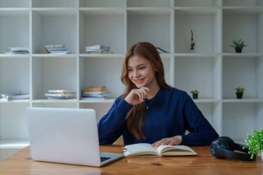 Mutlu Latin kız kolej öğrencisi uzaktan öğrenim kursu, uzak üniversite web sitesi ya da laptop üzerinden konuşma videosu alıyor ve evdeki ya da kampüsteki sanal toplantı seminerinde not defteri kullanıyor.