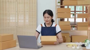 Küçük bir girişimin portresi, bir KME sahibi, bir Asyalı bayan girişimci ürünleri müşterilerle birlikte iç kutulara koymadan önce ürünleri düzenlemek için siparişleri kontrol ediyor. Serbest kavramlar