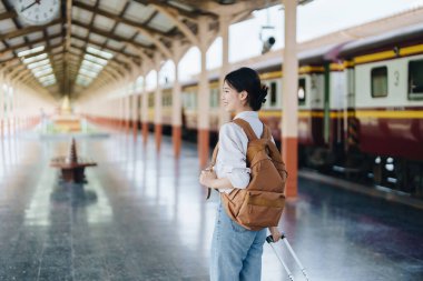 Turistler tren istasyonunda yolculuklarını beklerken mutlu yüz ifadeleri sergiliyorlar.