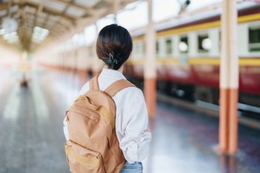 Turistler tren istasyonunda yolculuklarını beklerken mutlu yüz ifadeleri sergiliyorlar.