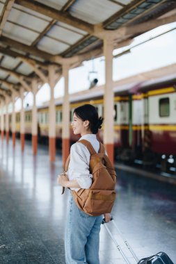 Turistler tren istasyonunda yolculuklarını beklerken mutlu yüz ifadeleri sergiliyorlar.