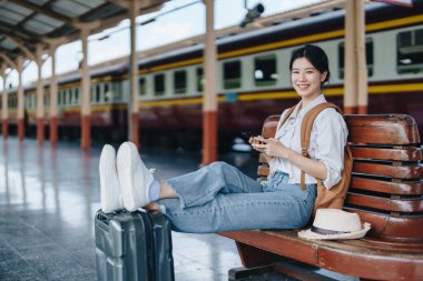 Turistler tren istasyonunda yolculuklarını beklerken mutlu yüz ifadeleri sergiliyorlar.