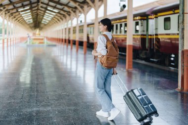 Turistler tren istasyonunda yolculuklarını beklerken mutlu yüz ifadeleri sergiliyorlar.