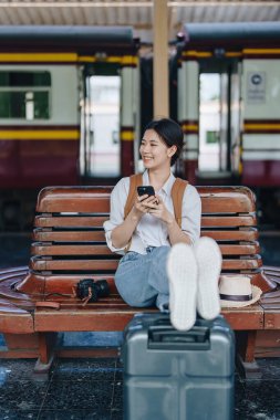 Turistler tren istasyonunda yolculuklarını beklerken mutlu yüz ifadeleri sergiliyorlar.