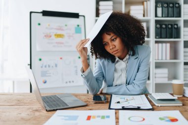 Stresli Amerikalı Yanmış Afrikalı iş kadını evrak işleri ile uğraşıyor. Migren saldırısı, serbest çalışma, ofiste çalışma..