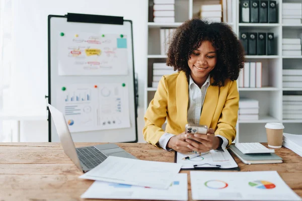 Akıllı telefon ve dizüstü bilgisayar kullanan Afrikalı kadın finansal belge, vergi, döviz, muhasebe ve mali danışman üzerinde çalışıyor..