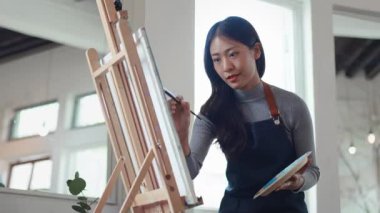 Güzel Asyalı kadın sanatçı soyut resim üzerinde çalışıyor, ressam modern sanat yaratıyor. Yüksek kalite 4k görüntü