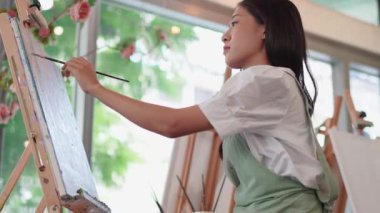 Güzel Asyalı kadın sanatçı soyut resim üzerinde çalışıyor, ressam modern sanat yaratıyor. Yüksek kalite 4k görüntü