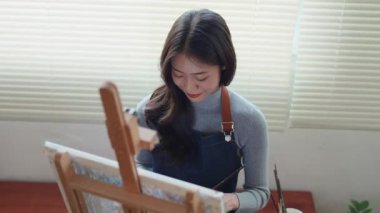 Güzel Asyalı kadın sanatçı soyut resim üzerinde çalışıyor, ressam modern sanat yaratıyor. Yüksek kalite 4k görüntü