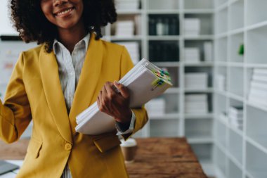 Güzel Afrikalı genç Amerikalı iş kadını dizüstü bilgisayar ve kağıt işlerini kullanarak finansal belge, vergi, döviz, muhasebe ve mali danışman üzerinde çalışıyor..