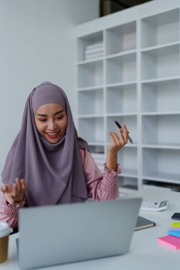 Müslüman kadın çalışanın iş sırasında bilgisayarla konferans vermesi